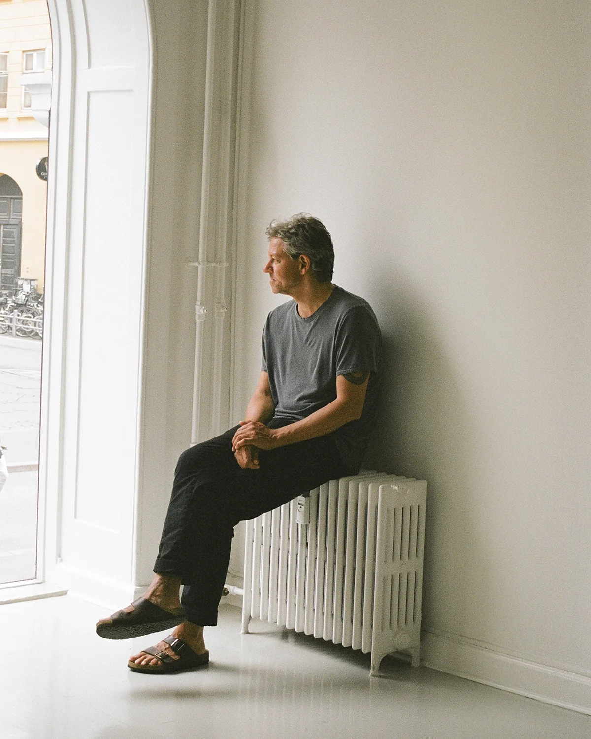A man seated by a window in a studio