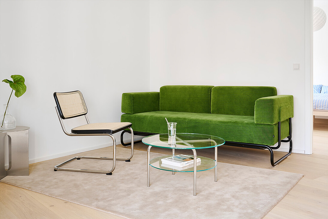 A cane cantilever chair and green sofa in a bright living room